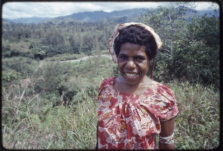 Western Highlands: smiling woman with tattooed face, river and mountains in background