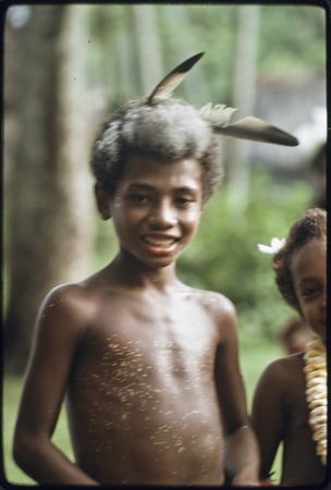 Dance: boy wears coconut oil and yellow pollen on skin, feathers and powder in hair, dressed up for dance