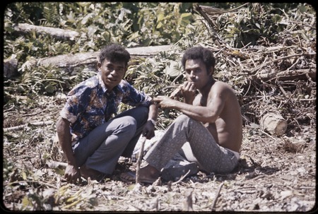 Land clearing: men take a break from cutting trees and bushes from rocky land, preparing for construction