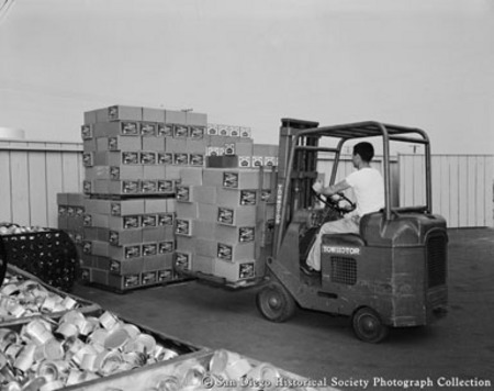 Man in fork lift stacking cases of tuna