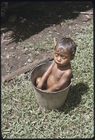 Young child bathes in a bucket of water