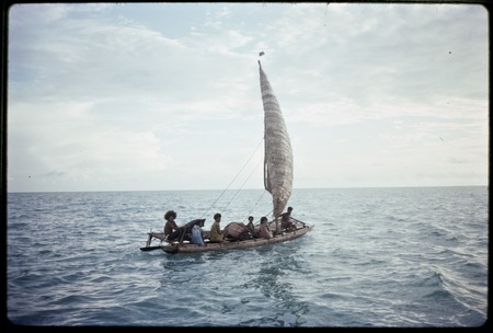 Canoe with woven pandanus sail, several passengers and some cargo