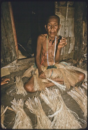 Weaving: Bomtavau, her head shaved in mourning, twists banana leaf fibers for skirt making