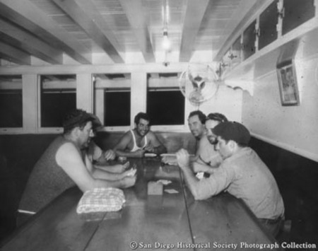 Fishermen playing cards below deck on tuna boat