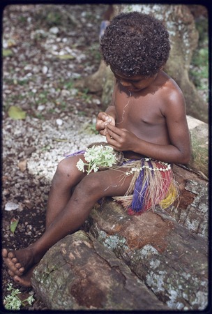 Child making a garland of small flowers