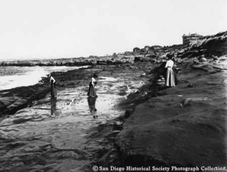 Exploring tide pools, four women on beach at La Jolla