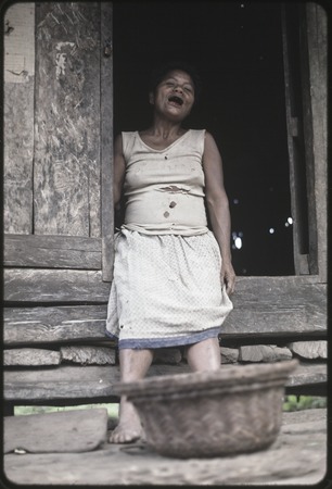 Woman sits in a doorway with basket at her feet