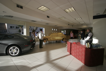 The Jewel / In God We Trust: junk car covered in gold leaf in luxury car dealer showroom