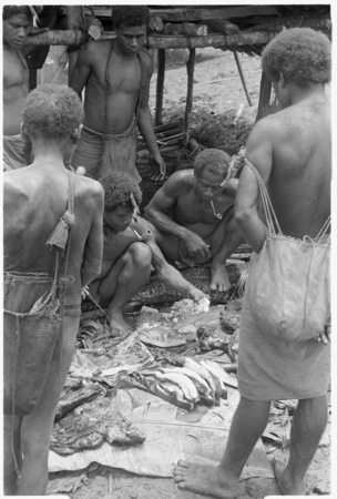 Men cutting up pork, to divide it for a mortuary feast.