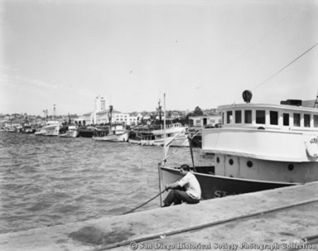 San Diego waterfront, Man sitting on dock and fishing boats along Embarcadero