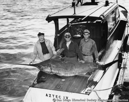 Three men posing with swordfish caught from sportfishing boat Aztec IV
