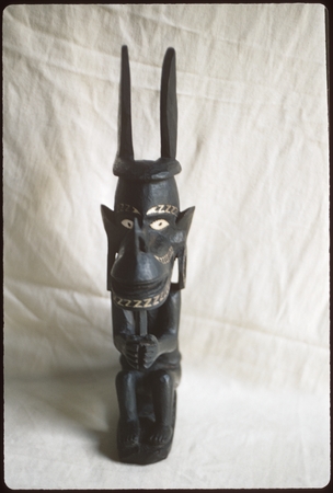 Canoe-prow figurehead sculpture of dark wood with inlay, seated figure