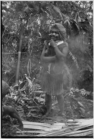 Pig festival, uprooting cordyline ritual, Tsembaga: smiling young woman in barkcloth cap, marsupial fur, and shell valuabl...