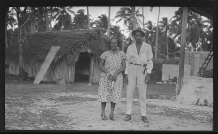 Cook Islands man and woman, house in background