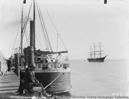Two men sitting on pier near docked ship Santa Cruz