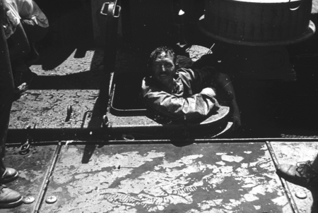 John D. (John Dove) Isaacs climbing in or out of a compartment hole on a ship during the Capricorn Expedition (1952-1953)....