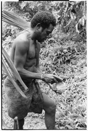 Wiri, high priest for this group, breaks coconut with rock as part of ritual.