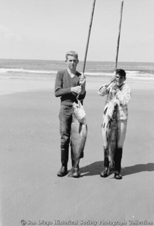 Two boys posing with fishing rods and fish caught from surf fishing at La Jolla