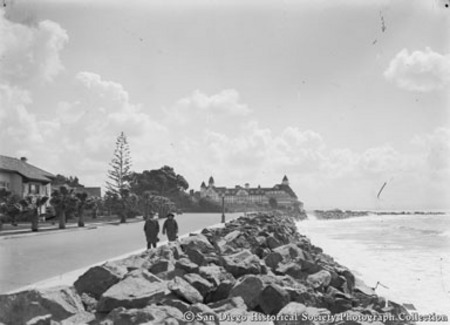 Two people walking on Ocean Boulevard next to sea wall on Coronado shoreline