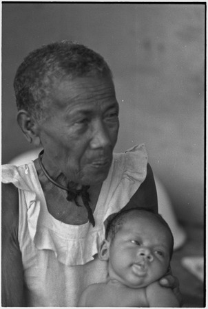 Elderly woman, Bomtavau, holding young infant, perhaps her grandchild