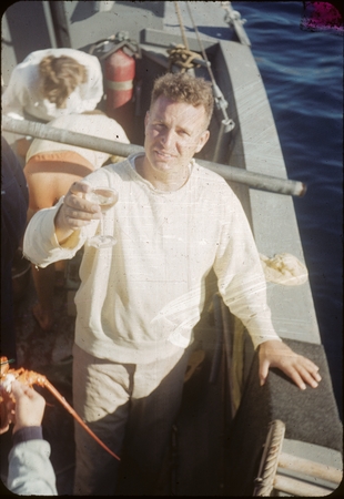 Robert S. Dietz lifting a wine glass aboard ship
