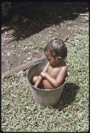 Young child bathes in a bucket of water