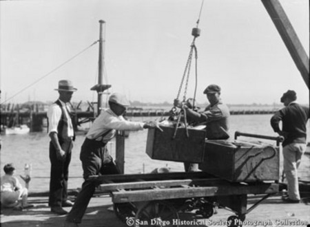 Dock workers hoisting crate of fish for Van Camp Sea Food Company