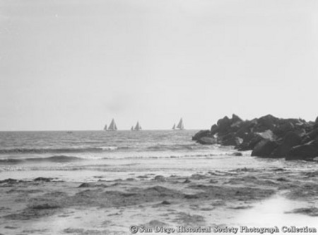 Rock jetty and sailboats on Pacific Ocean off coast of Coronado