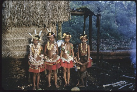Girls are adorned with face paint, short red fiber skirts, flower garlands, and other items, beautified for a dance