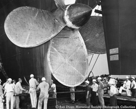 Workers standing below giant ship&#39;s propeller at National Steel and Shipbuilding Company