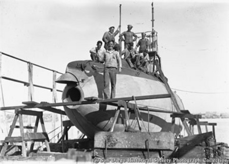 Crew posing with U.S. Navy submarine in drydock