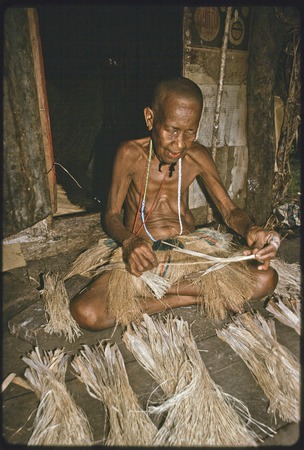 Weaving: Bomtavau, her head shaved as a sign of mourning, twists banana leaf fibers for skirt making