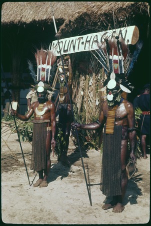 Mount Hagen show: Medlpa men with elaborate headdresses, pearl shell valuables and other finery pose in front of a sign