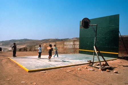 The Rules of the Game: ball court and border fence with children playing