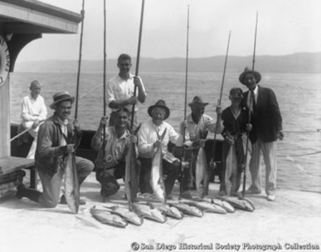 Fishermen with rods posing with catch of yellowtail tuna on deck of Point Loma fishing barge