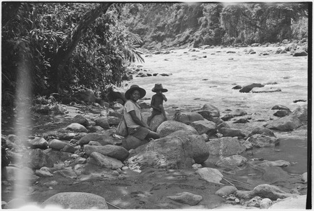 Simbai River Valley: man and child relax on bank of a large river