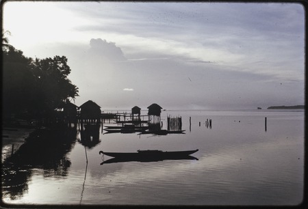 Manus: dawn at Pere bay, tethered canoes, houses and outhouses over calm lagoon
