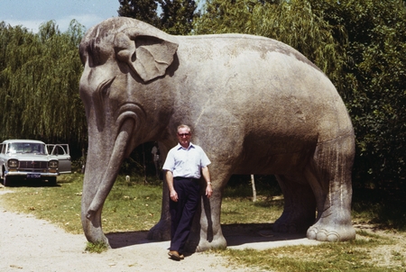 [Henry William Menard standing before a stone elephant]