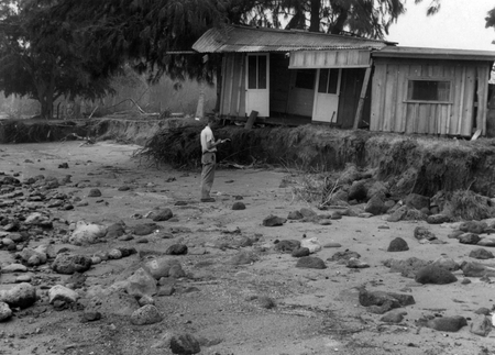 Francis P. Shepard, from Scripps Institution of Oceanography, inspecting tsunami damage to a house and scarp formation, at...