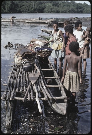 Canoes: women load baskets of produce and other items onto canoe used for coastal transport