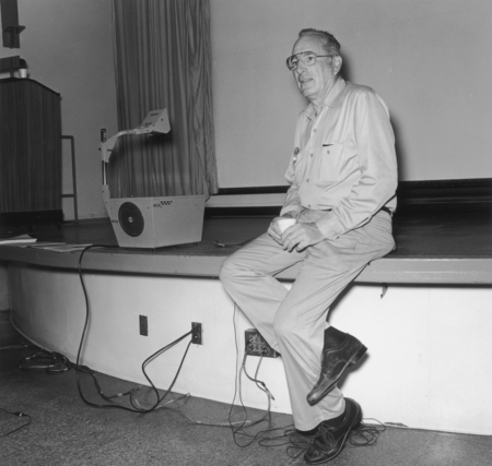 William A. Nierenberg sitting on the stage, Sumner Auditorium, Scripps Institution of Oceanography