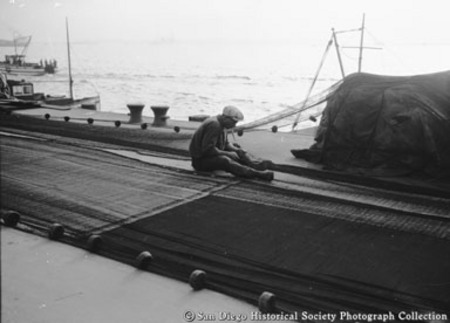 Fisherman mending net on dock
