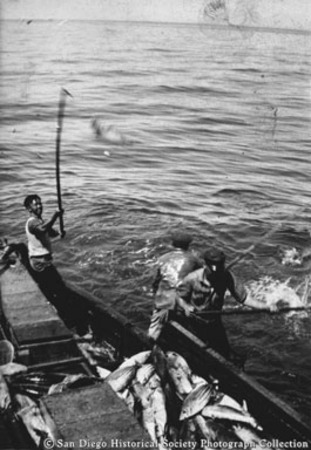 Chinese Americans fishing with bamboo poles from side of boat