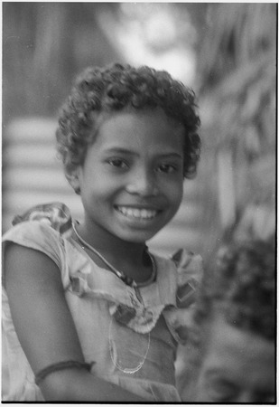 Young girl smiling, wearing a small shell bead necklace