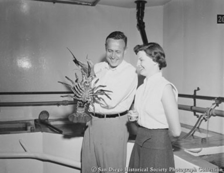 Woman looking at lobster held by Dr. Roger Revelle at Scripps Institution of Oceanography