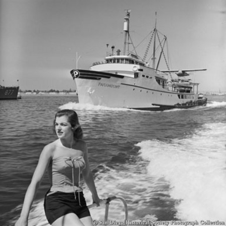 Tuna boat Paramount with airplane on stern canopy coming into port, woman on boat in foreground