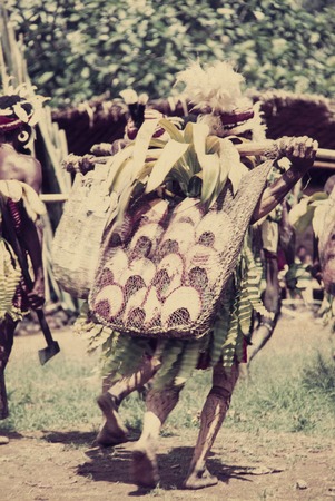 Decorated men displaying pearlshells to be exchanged in Koiari village; shells are carried in a large netbag