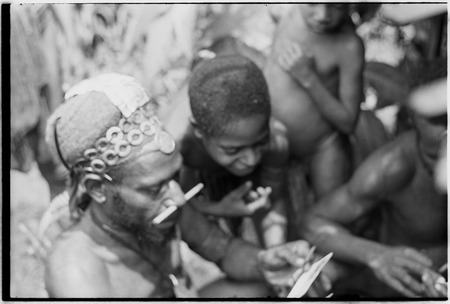 Pfun, a luluai, and children examine photographs