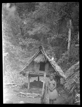 Woman in front of house at Wamea (Dum Dum) Island, Milne Bay