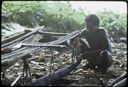 Canoe-building: man works on outrigger supports for a canoe